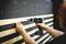 A person is installing wooden battens on a black wall using a cordless drill.