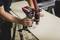 A person is cutting a wooden board with an electric tool. Straight cuts are being made while wood shavings are being extracted.