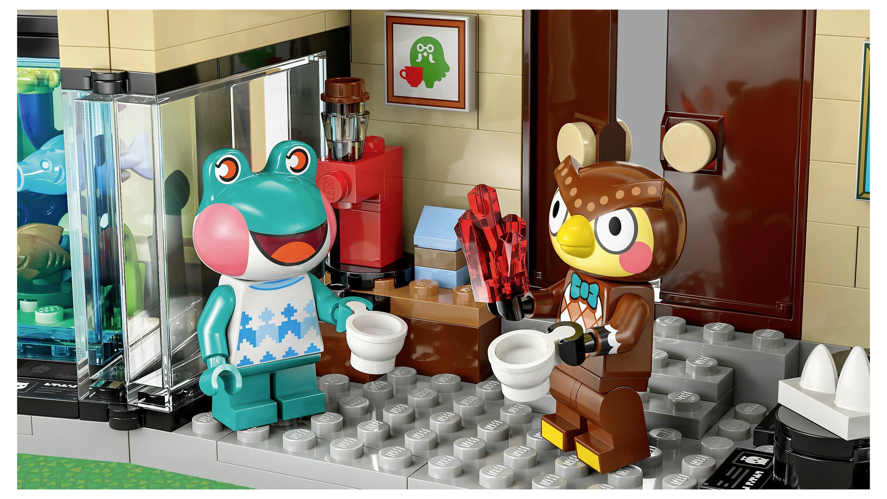 A frog and an owl LEGO characters hold white cups, standing in a toy room. A colorful artwork and a dispenser are visible in the background.