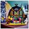 A colorful toy haunted house with a large mouth opening, surrounded by LEGO flowers and a skeleton figure, against a blurred background.