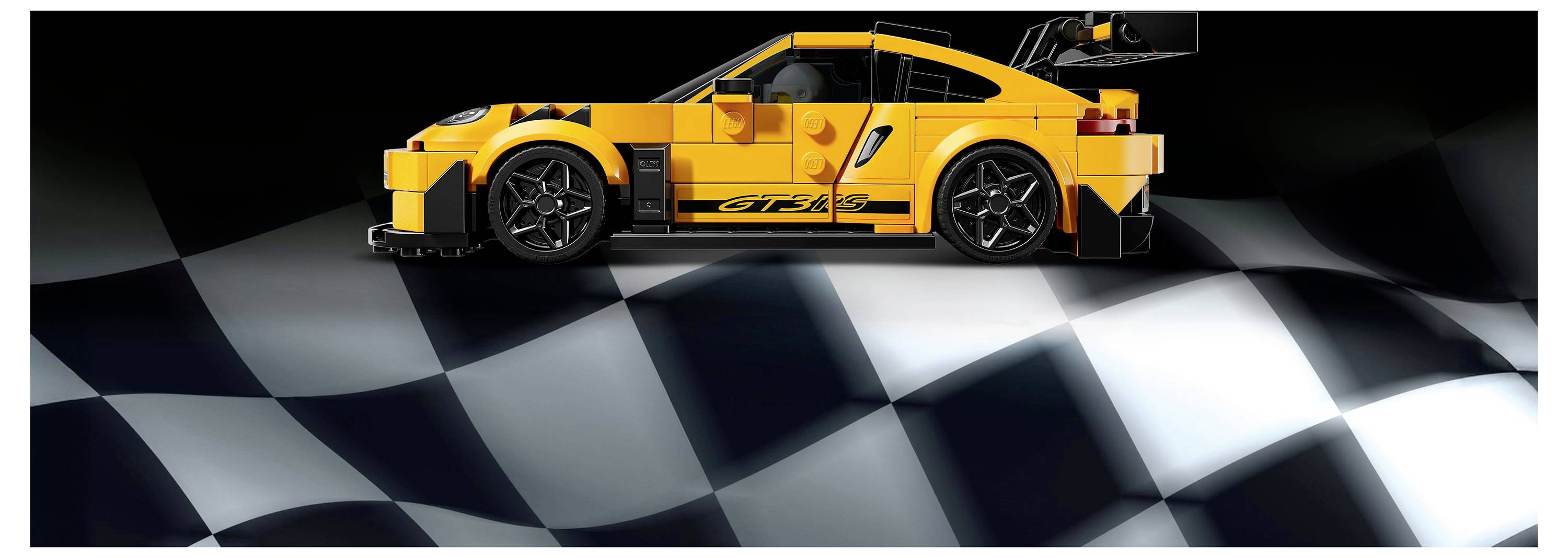 A detailed yellow toy sports car on a black and white checkered background, resembling a racetrack, viewed from the side.