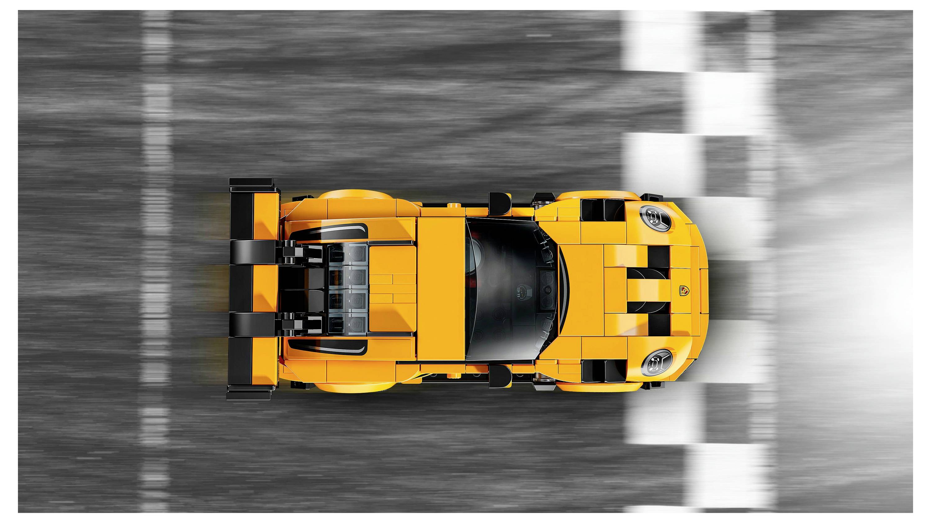 Aerial view of an orange sports car crossing a finish line on a racetrack.