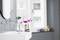 A stylish bathroom with a round mirror above a white sink. A magnifying mirror sits on the basin's edge.