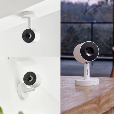 Two white Netatmo surveillance cameras, one mounted on the ceiling and the other standing on a table, both with a modern design.