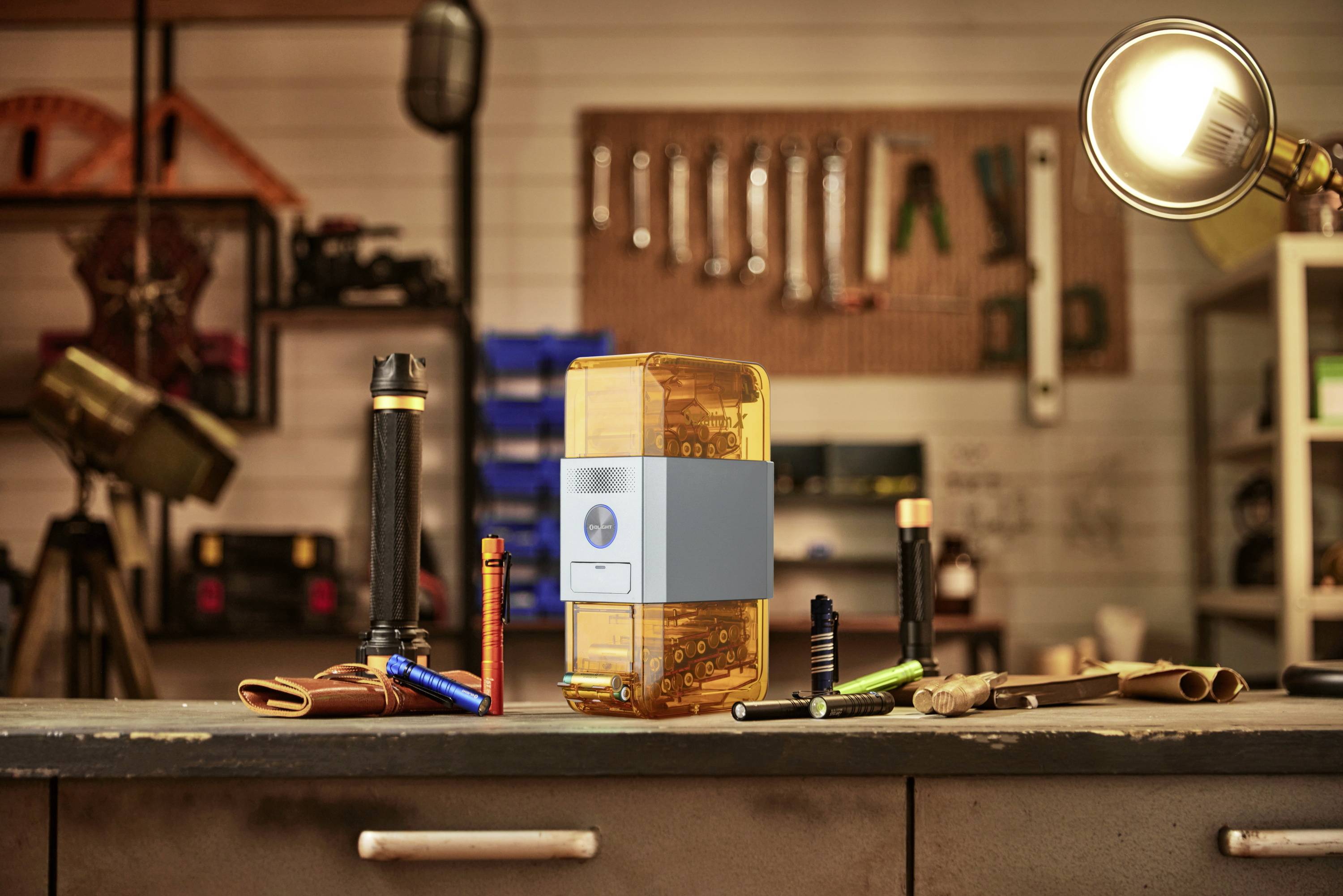 Workbench with torches, power tools and tools in the background. Focus on an orange device in the centre.
