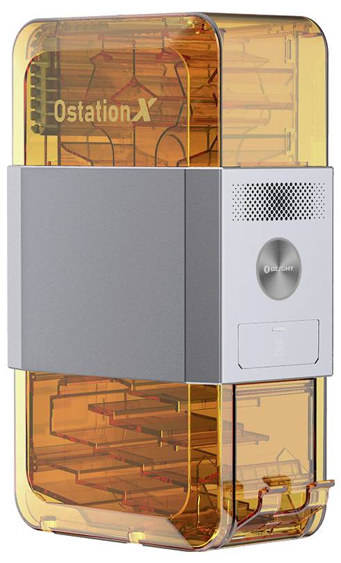An orange-translucent 3D printer enclosure with the inscription 'OstationX'. Control buttons and a speaker are located on the front panel.