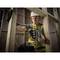 A construction worker wearing protective clothing is drilling into a wooden frame with a cordless drill on a building site.