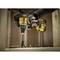 A person is using a cordless drill to bore a hole into a wooden board. Wood shavings are flying around.
