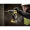 A person wearing safety glasses is drilling into a concrete wall with a cordless drill.
