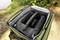 A portable drum machine in an opened, padded case, surrounded by green nature.