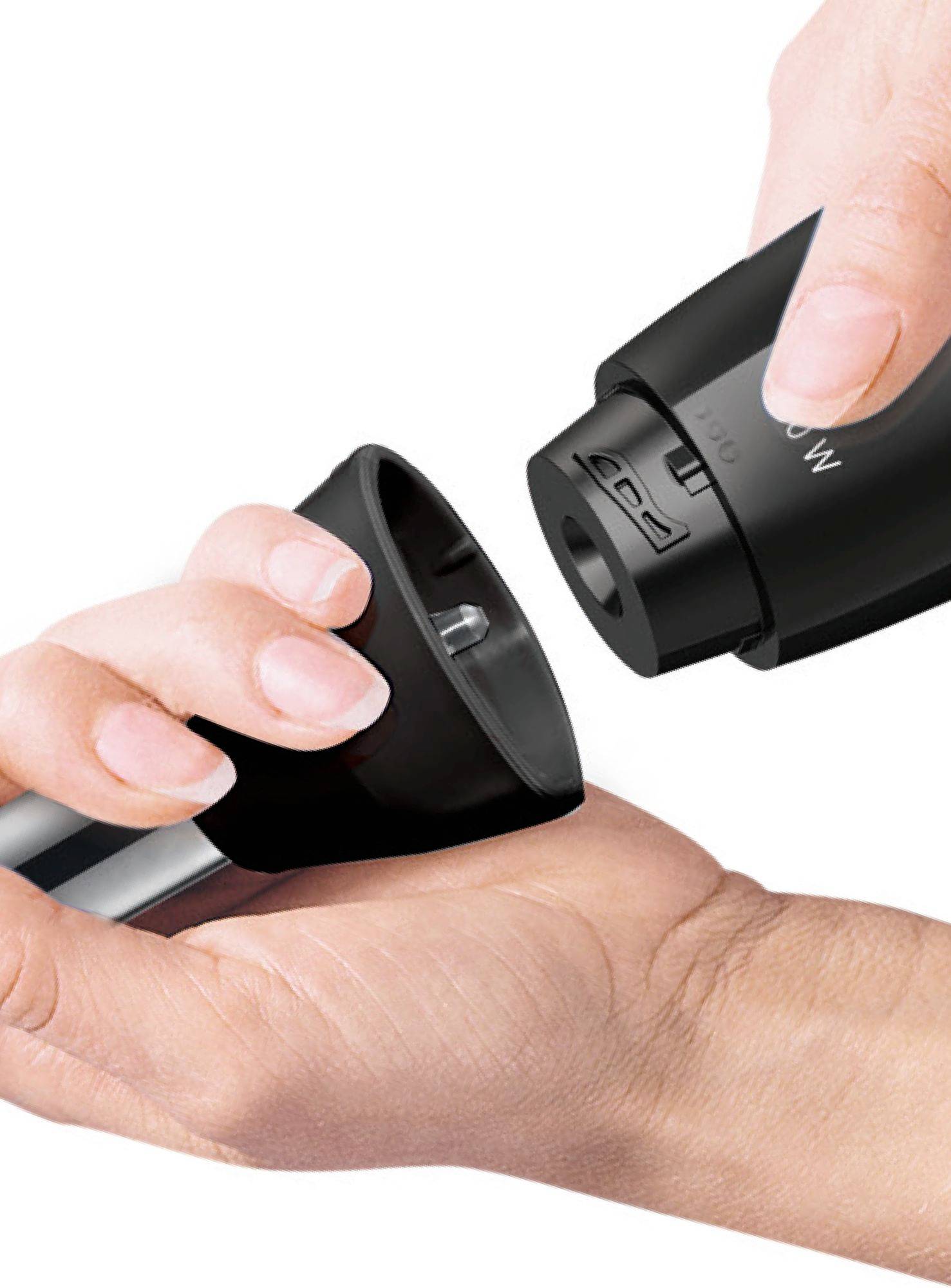 A person is holding an electric milk frother, removing the lid. Focus on the handling of the device.