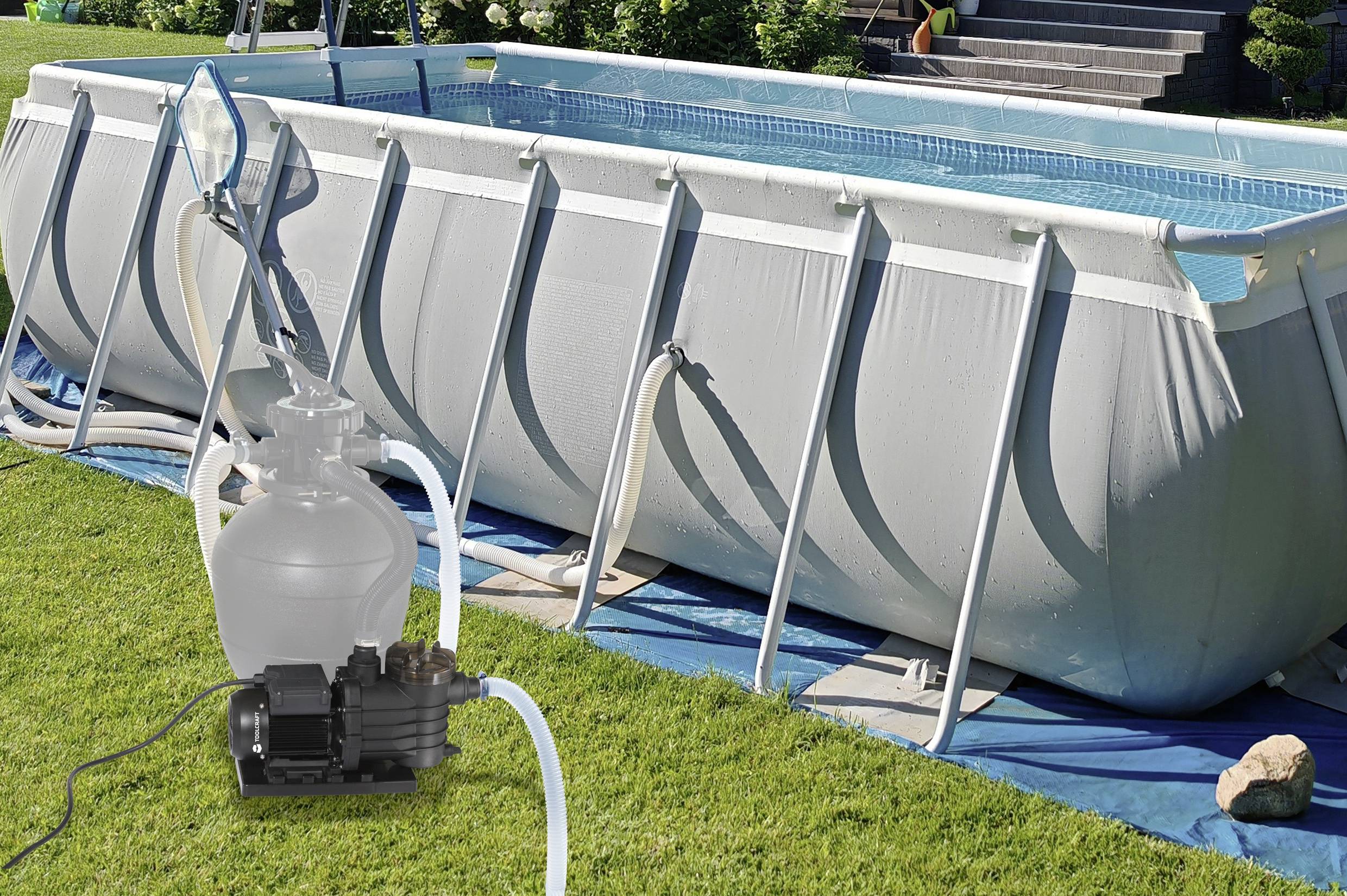 'An above-ground pool with a white frame and blue liner sits on a lawn. A pool filter pump is connected, with hoses running to the pool.'