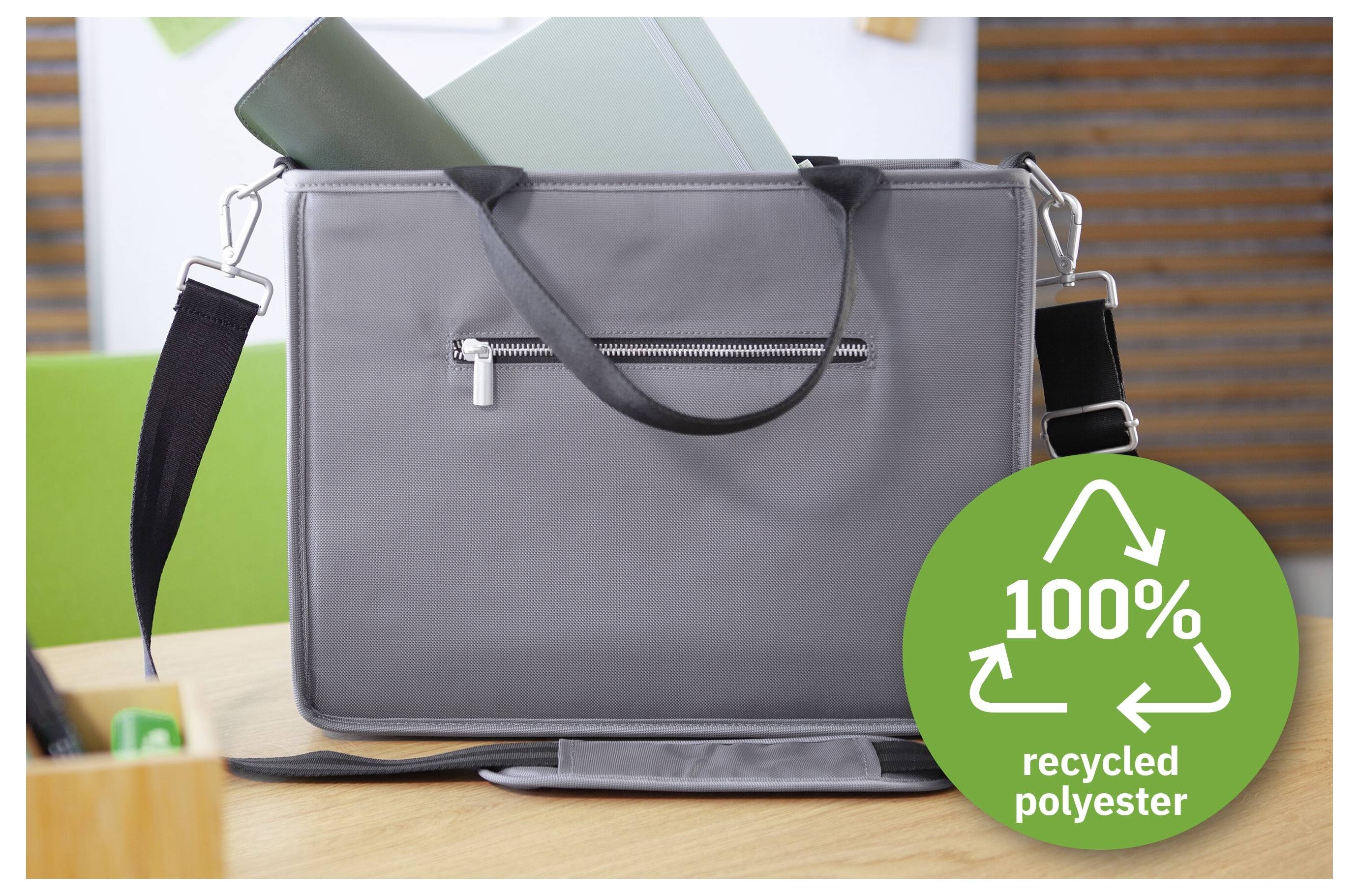 Gray shoulder bag on a desk with green folders behind it, labeled with a green badge reading '100% recycled polyester'.<br>
