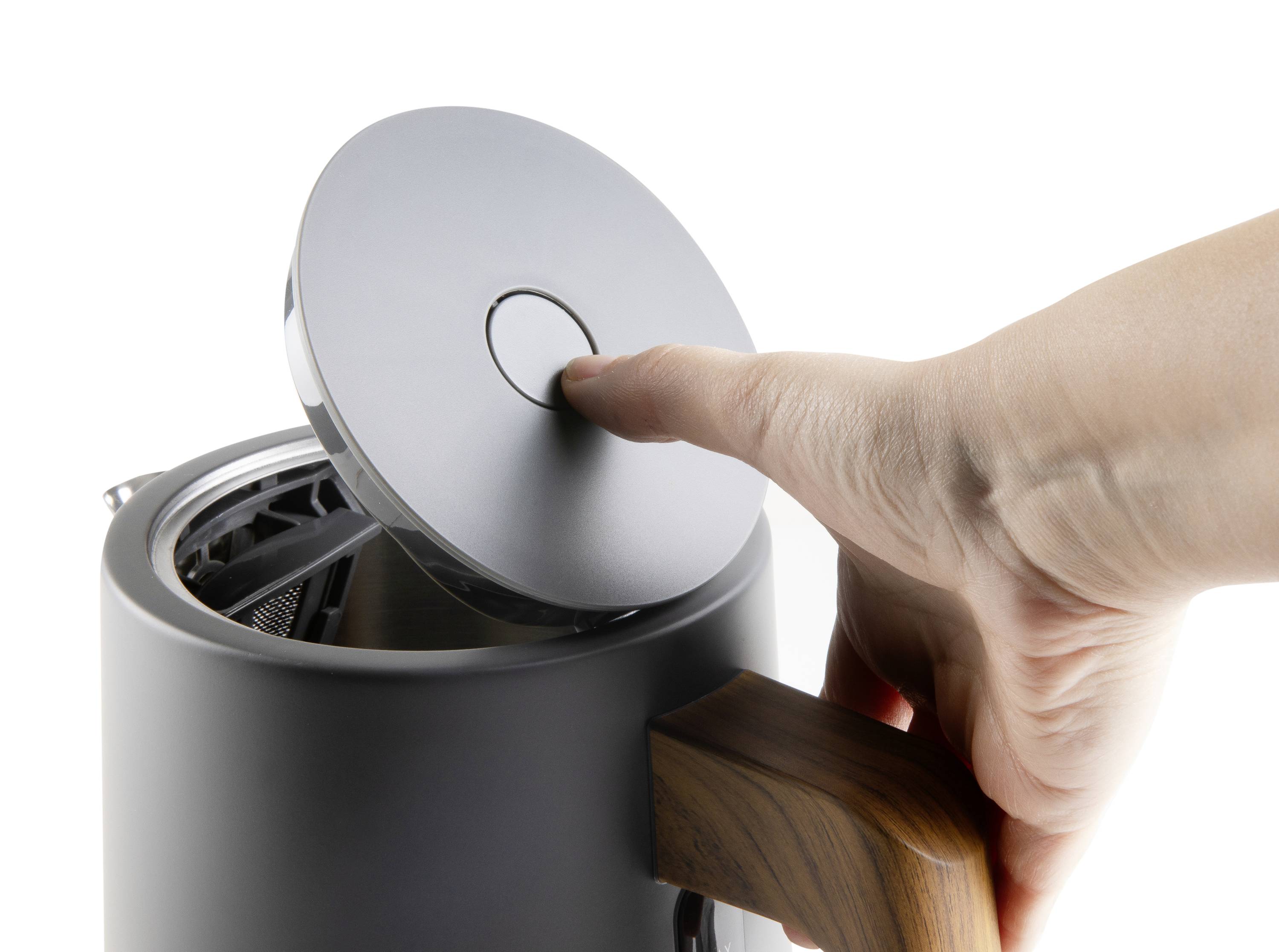 A finger opens the lid of a modern kettle with a wooden handle. The kettle is finished in a silver-grey colour.