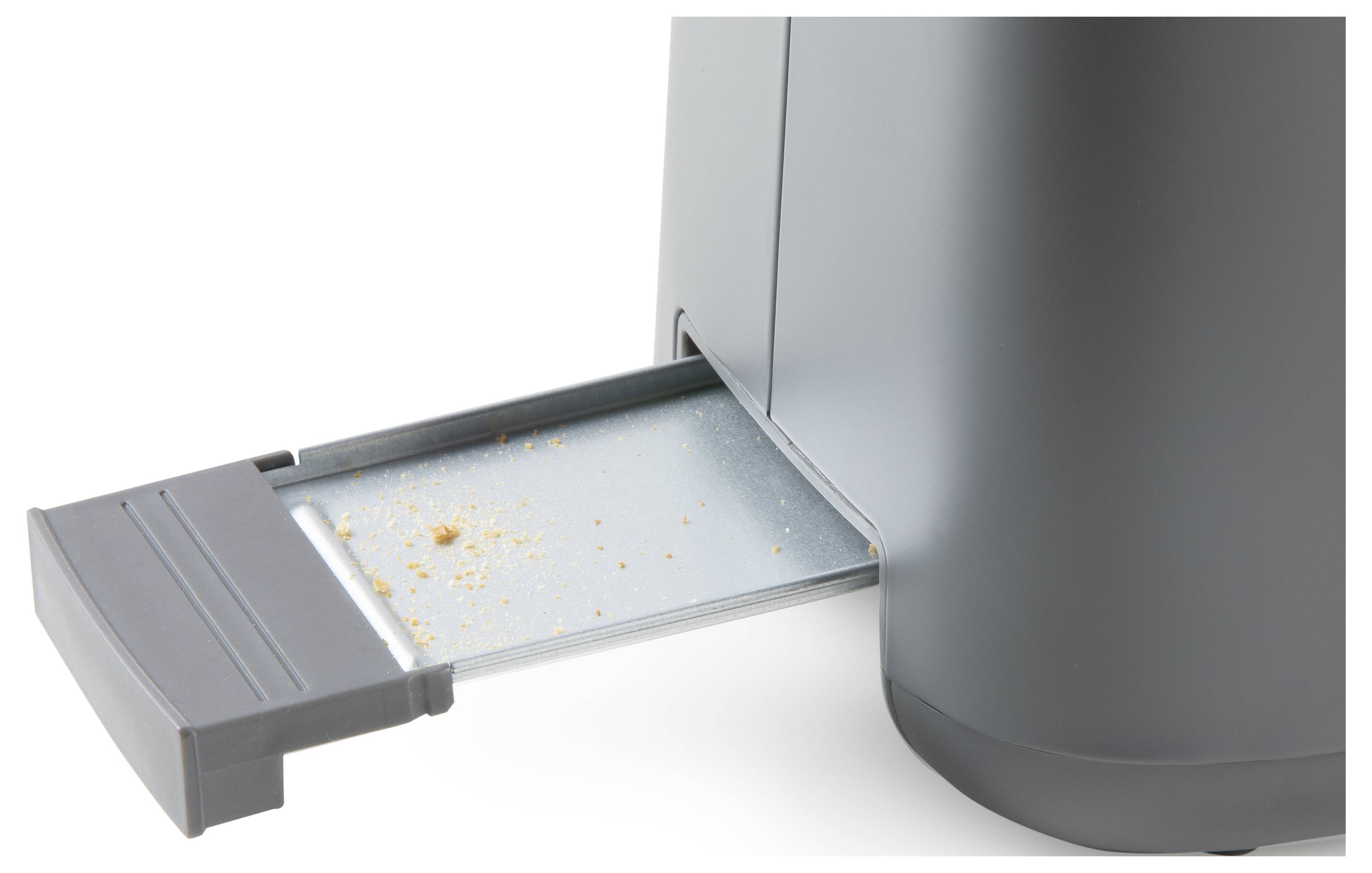 A pulled-out crumb tray of a grey toaster shows breadcrumbs.