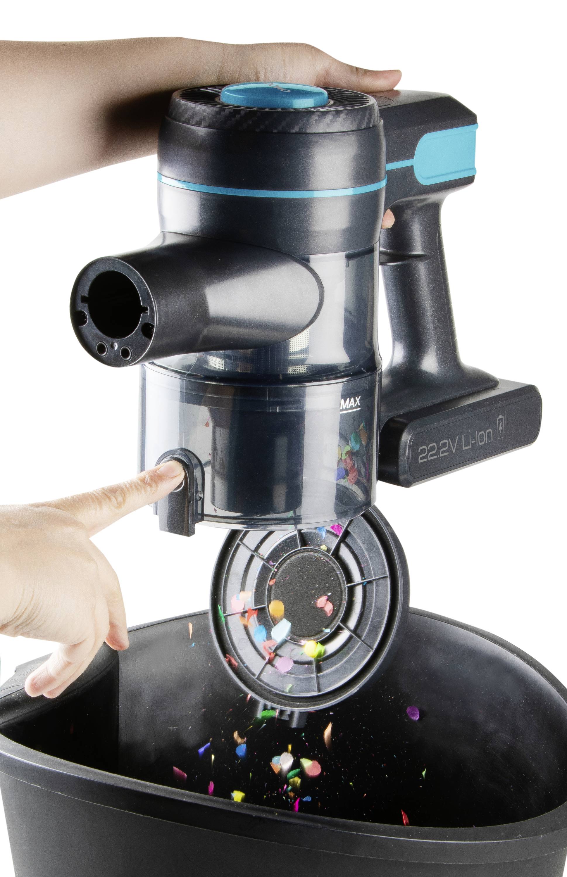 A hand is operating a handheld vacuum cleaner, emptying dirt and colourful particles over a rubbish bin.