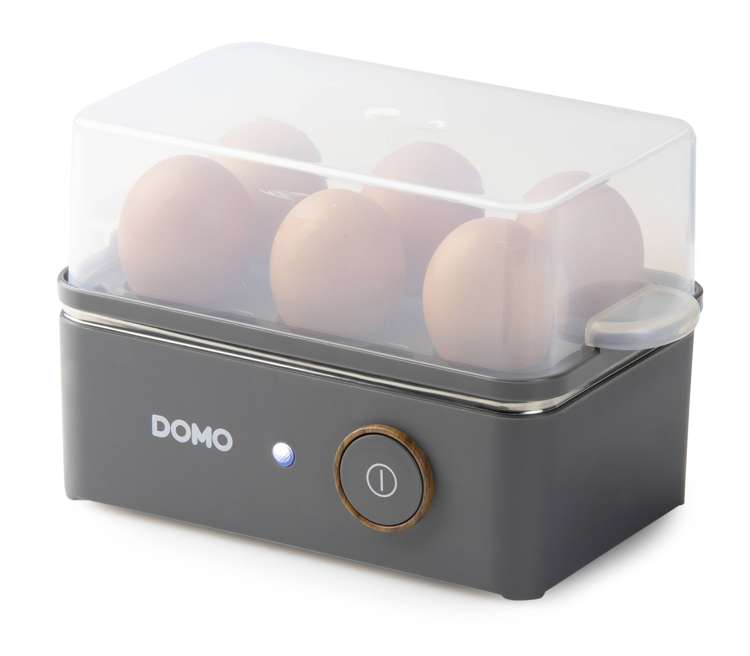 An electric egg cooker with a transparent lid, capable of cooking six eggs. The device has a black base with an indicator light and an on/off switch.