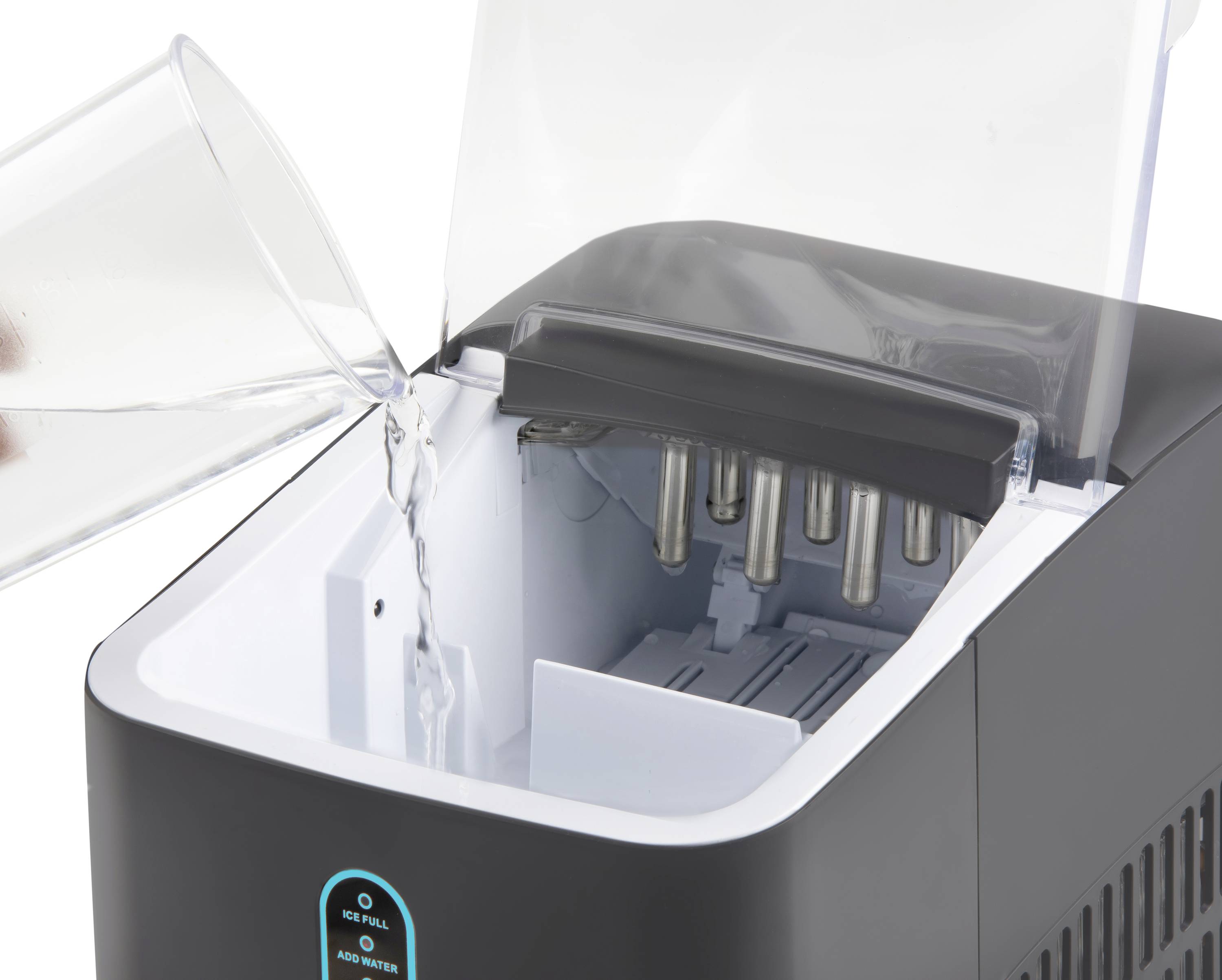 A glass of water is poured into a black ice machine with an open lid. The machine has a digital display at the front.