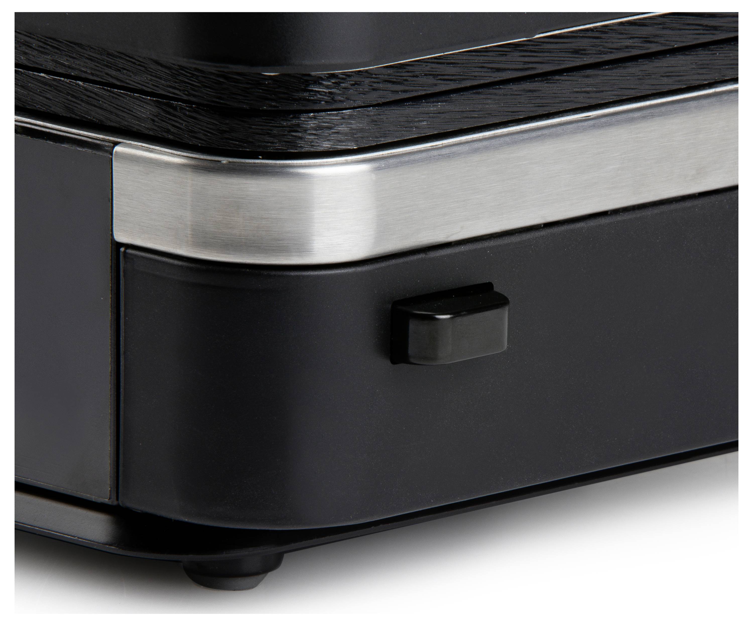 Close-up of a kitchen appliance control element with a black button and silver metal surround, showing design details.