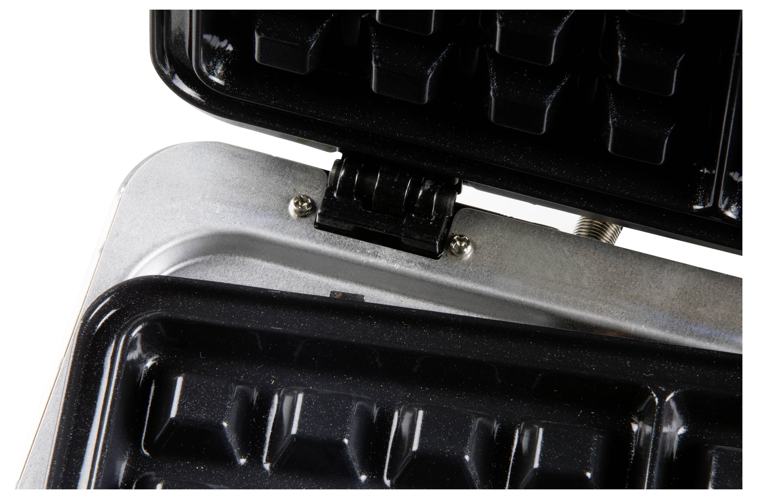 A waffle iron in close-up with an opened black, cast iron plate on which waffles can be baked.