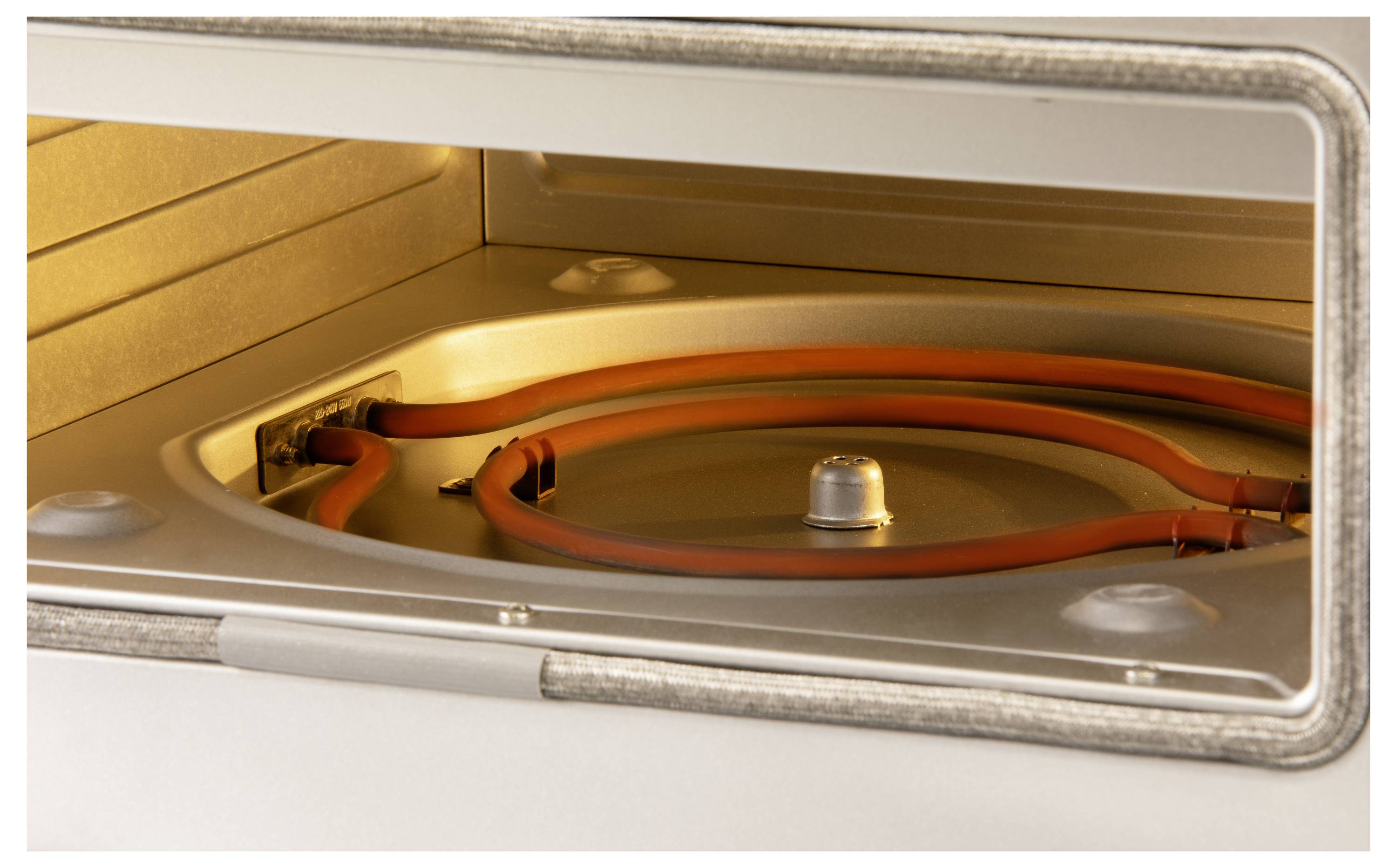 An open oven with a visible heating element on the ceiling, light on and metallic inner walls.