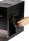 A hand removes or replaces a component on the side of a black machine, presumably a coffee maker.