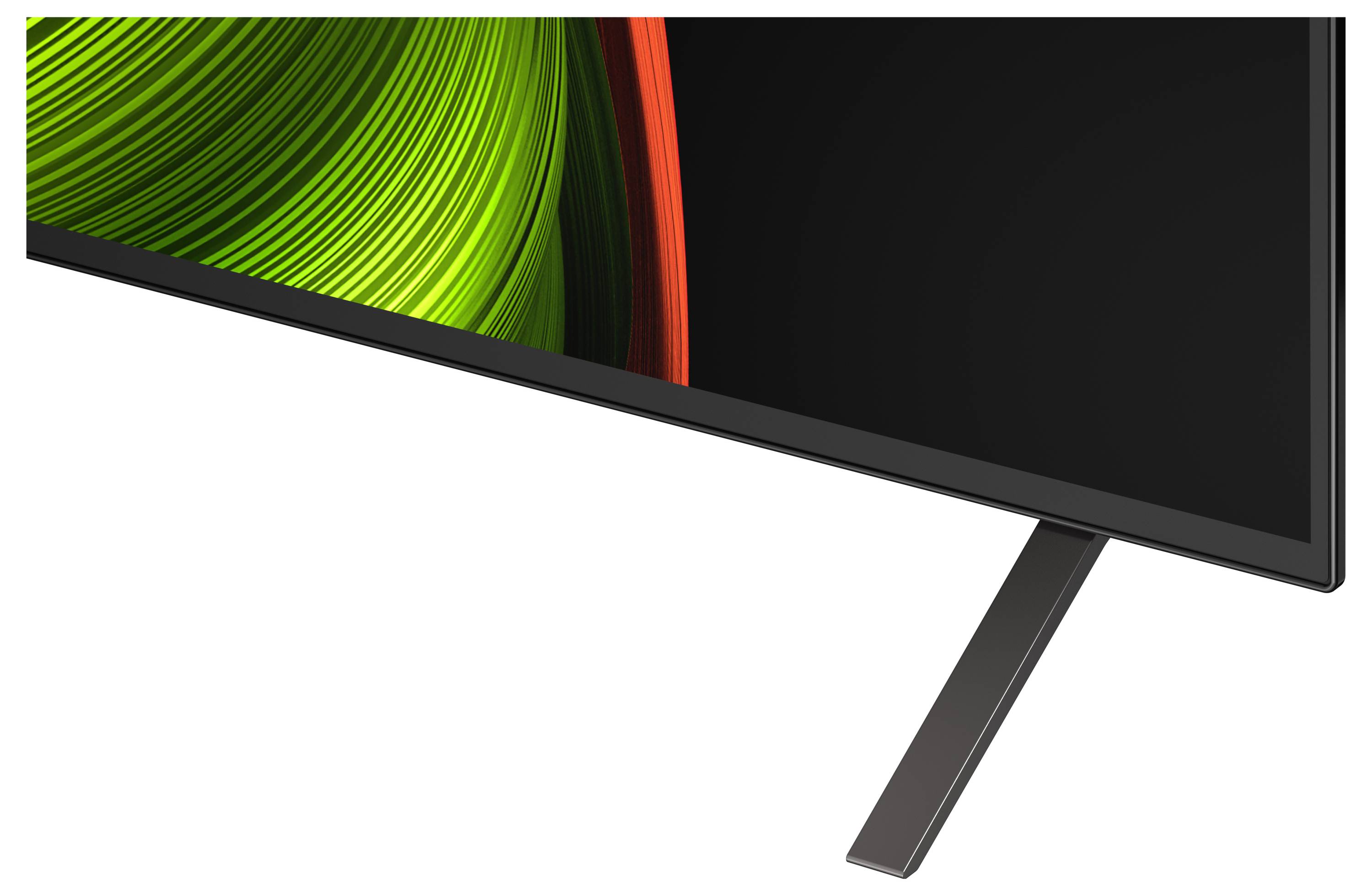 A modern flat-screen TV corner showcasing a sleek metallic stand, with vibrant green and red abstract patterns displayed on the screen.