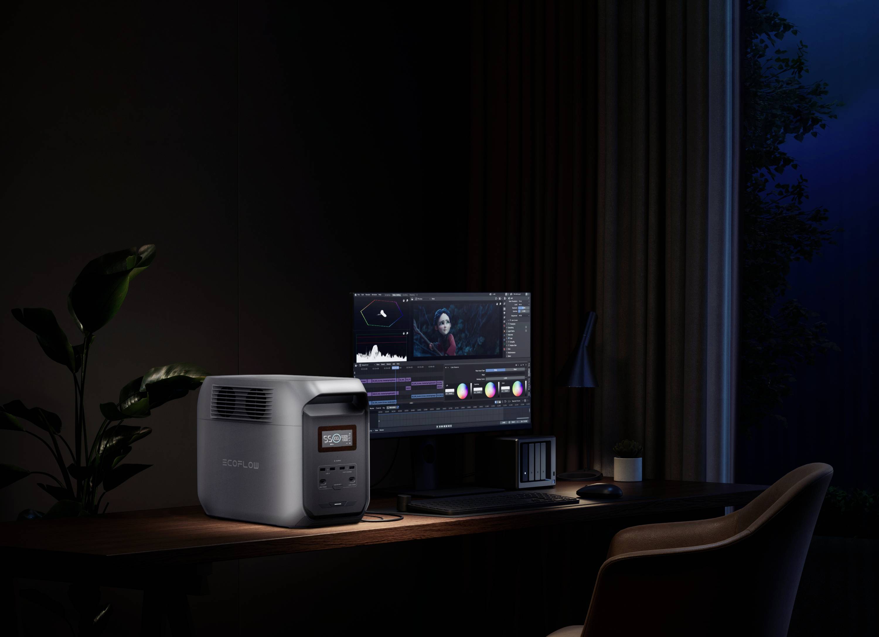 Computer workstation at night with a monitor displaying a video editing program, next to a large battery showing 99% charge.