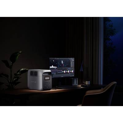 Computer workstation at night with a monitor displaying a video editing program, next to a large battery showing 99% charge.