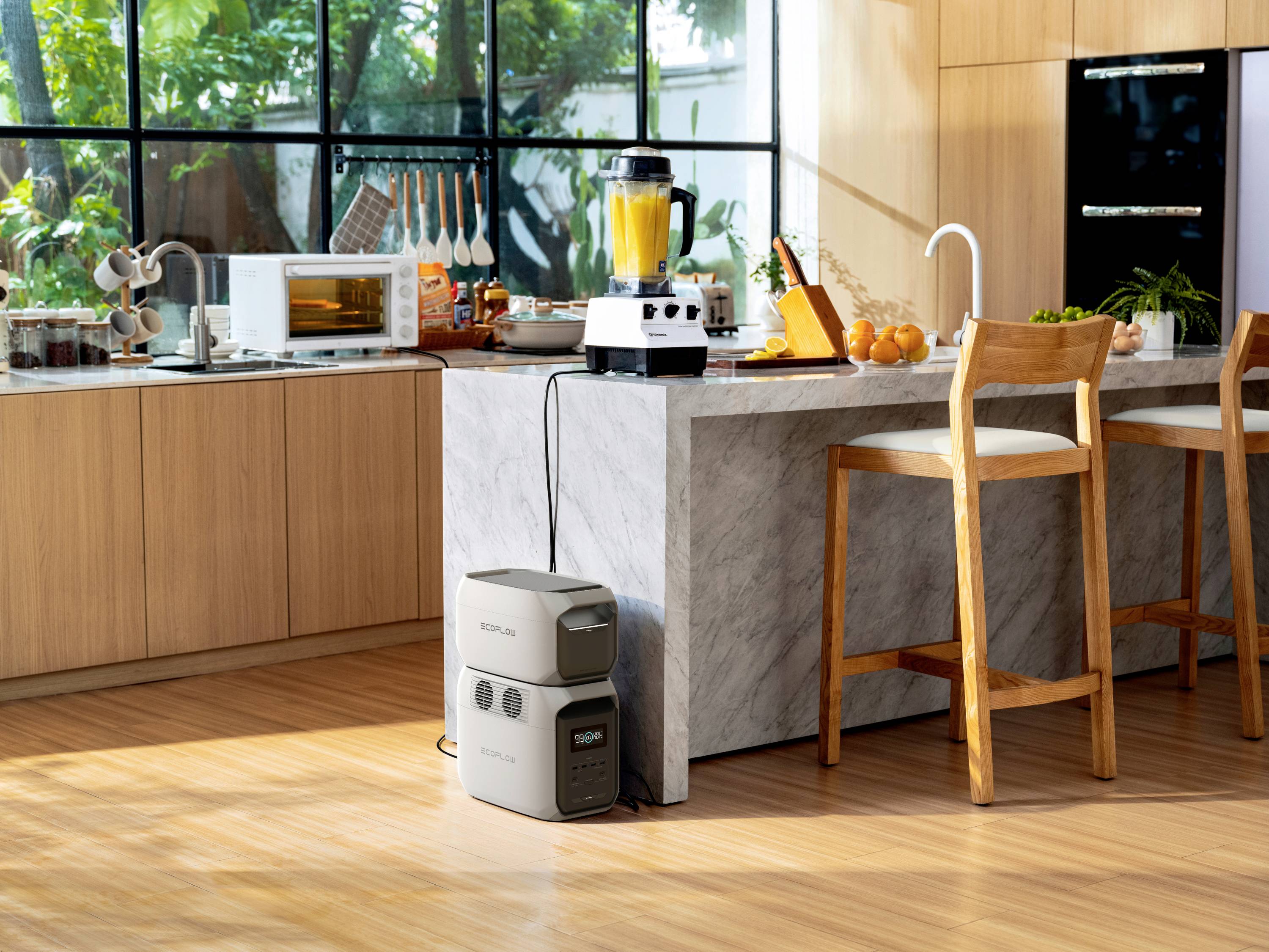 A modern kitchen with wooden and marble elements. On the worktop are a blender, fruit and a toaster. Portable power supply unit on the floor.