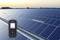 A measuring device shows a diagram in front of a large solar park at sunset, symbolising solar installation performance monitoring.
