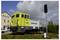 A small yellow locomotive with the 'Captrain' inscription stands on a section of track outdoors. A building is visible in the background.