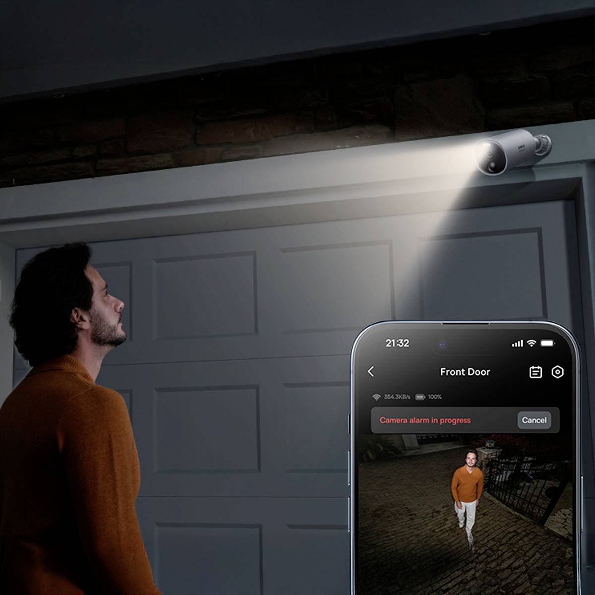 A man is standing in front of a closed door. A camera recording of the man is displayed on a smartphone screen.