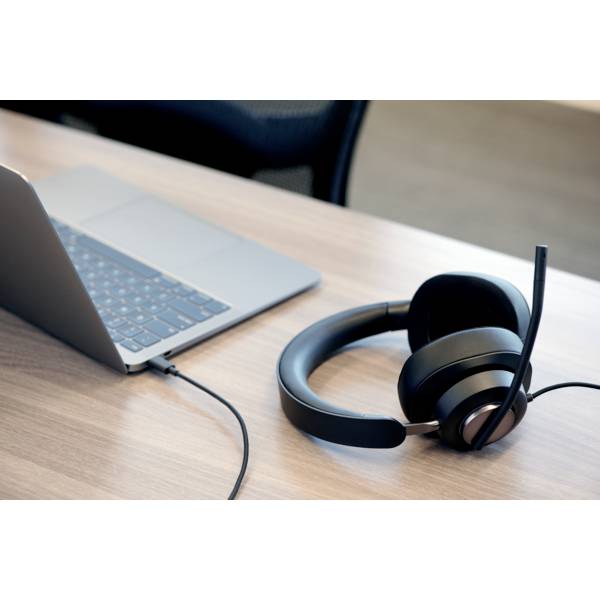 Laptop on a wooden table, connected to a black headset. Perfect for video conferences or online work.