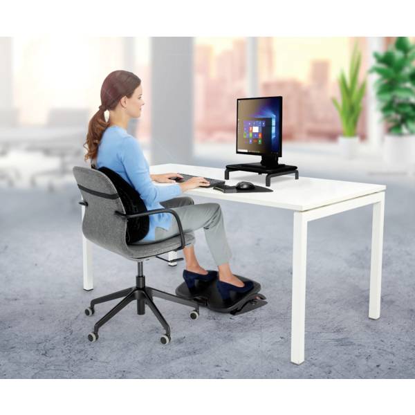 A woman is sitting ergonomically correctly at a desk, using a computer with a raised screen. Plants can be seen in the background.