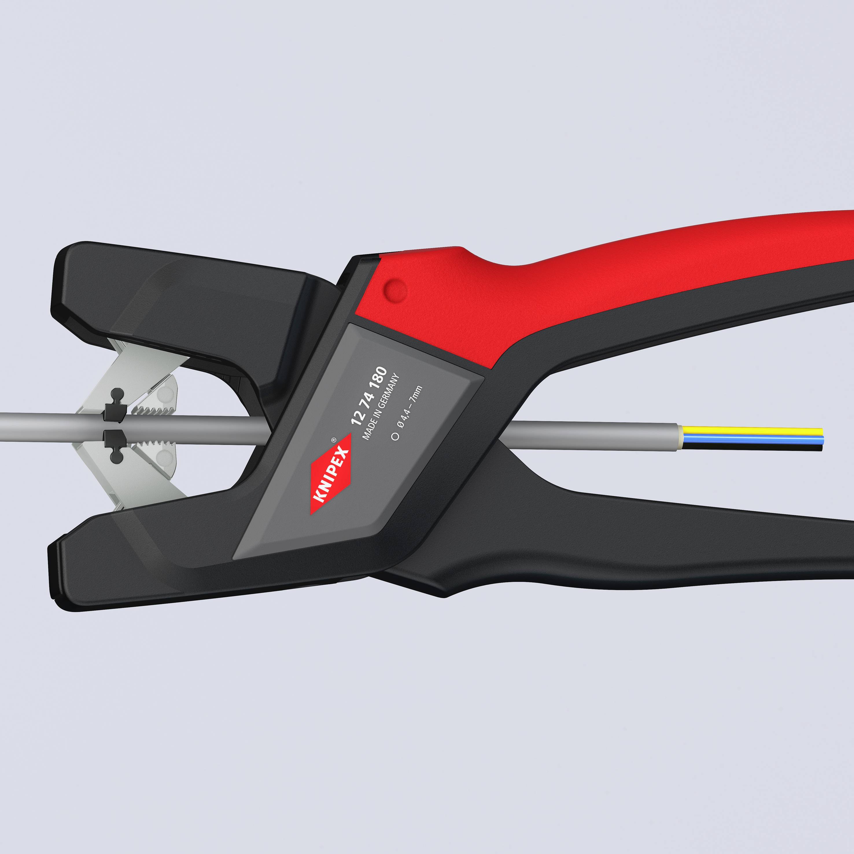 The wire stripper in black and red cuts through a cable. It is a tool used for removing the insulation from cables.