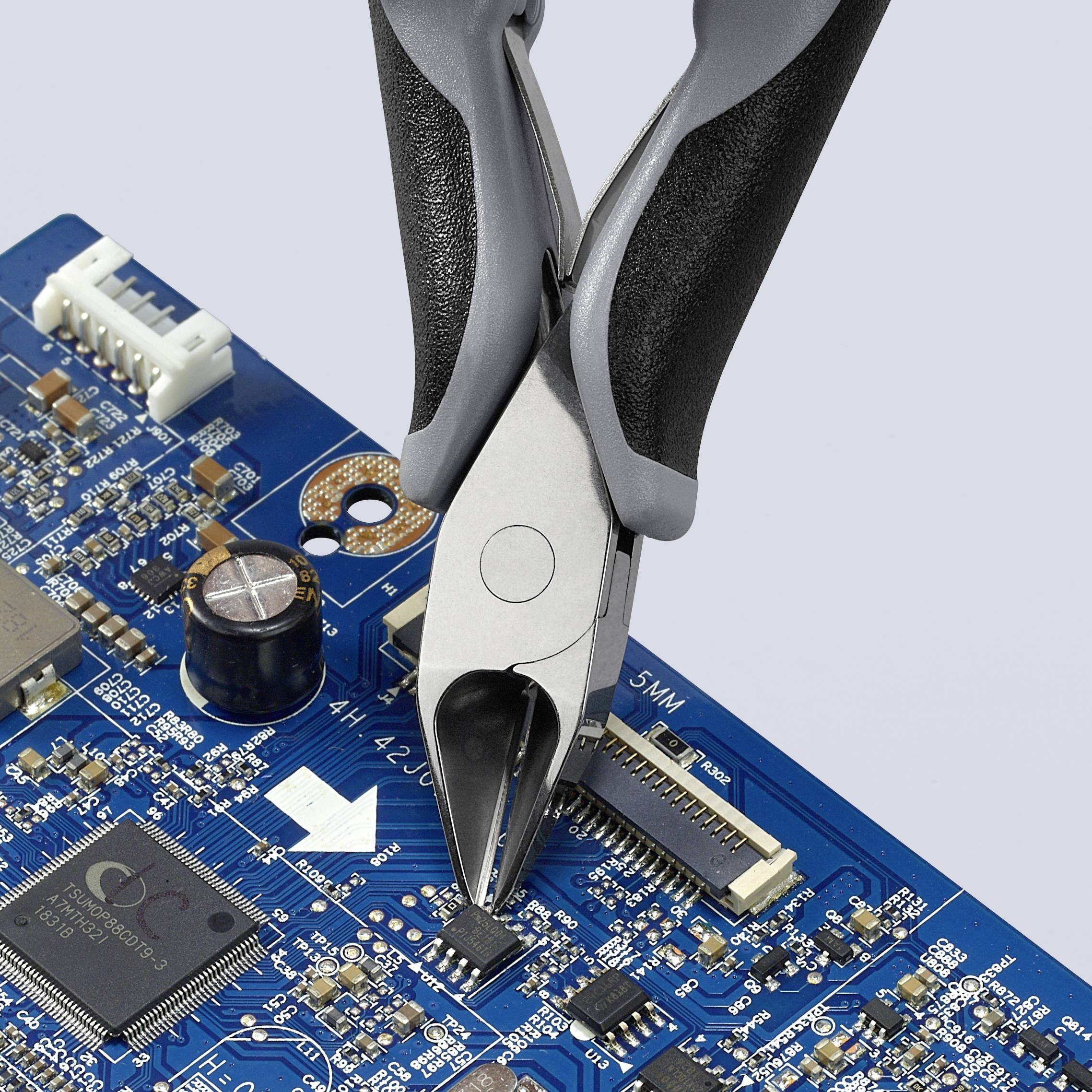 A pair of pliers holds an electronic component on a blue circuit board, surrounded by additional circuitry and components.