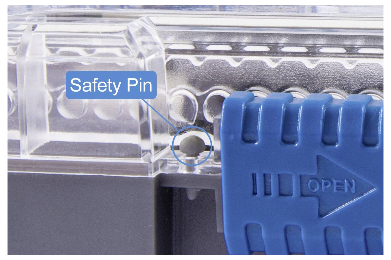 Close-up of a blue lever labeled 'OPEN' with a safety pin slot highlighted, indicating a locking mechanism on a transparent container.