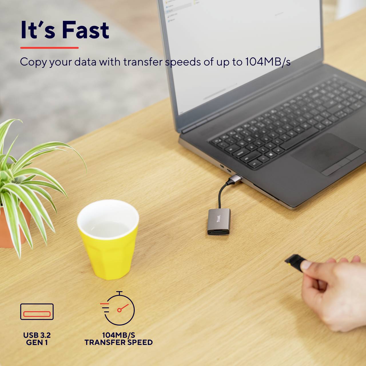 A laptop on a table, connected to a small storage module. Text says: 'It's Fast' and '104MB/s Transfer Speed'.