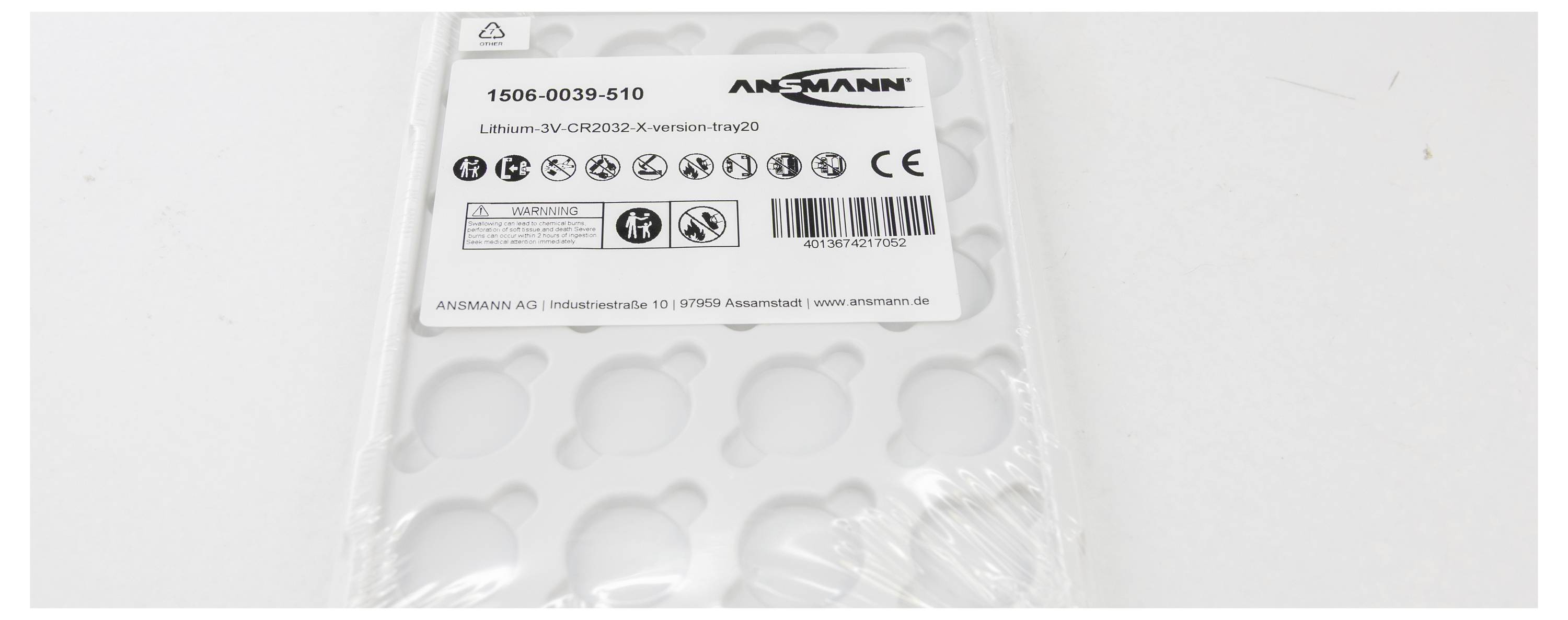 Packaging for CR2032 batteries by Ansmann, showing symbols and instructions. Packaging is open, batteries are missing.