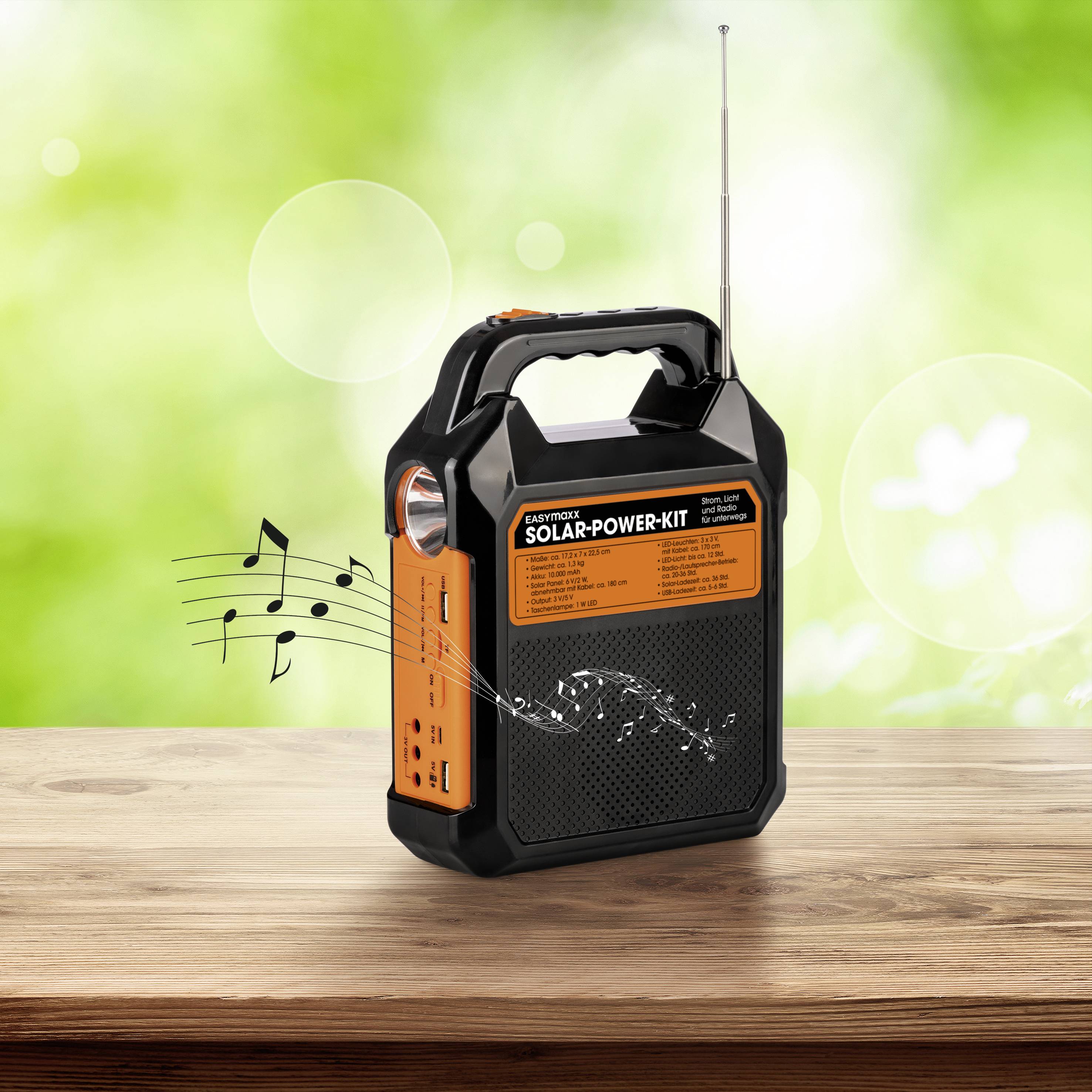 A portable, orange and black solar radio compact device on a wooden table. Musical notes indicate it is playing music. Background green and blurred.