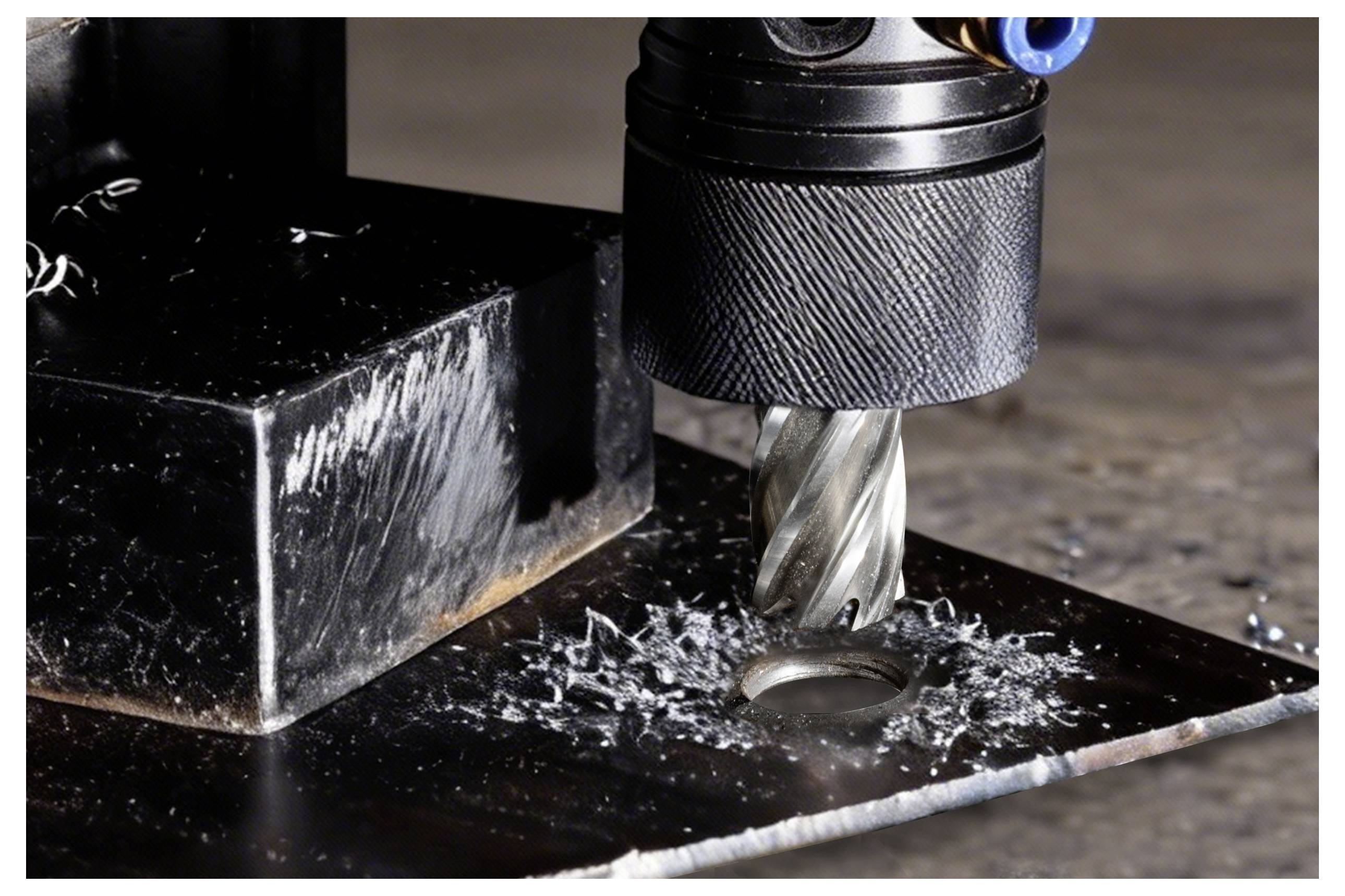 A metal drill bit cutting through a piece of metal, creating metal shavings around the hole.