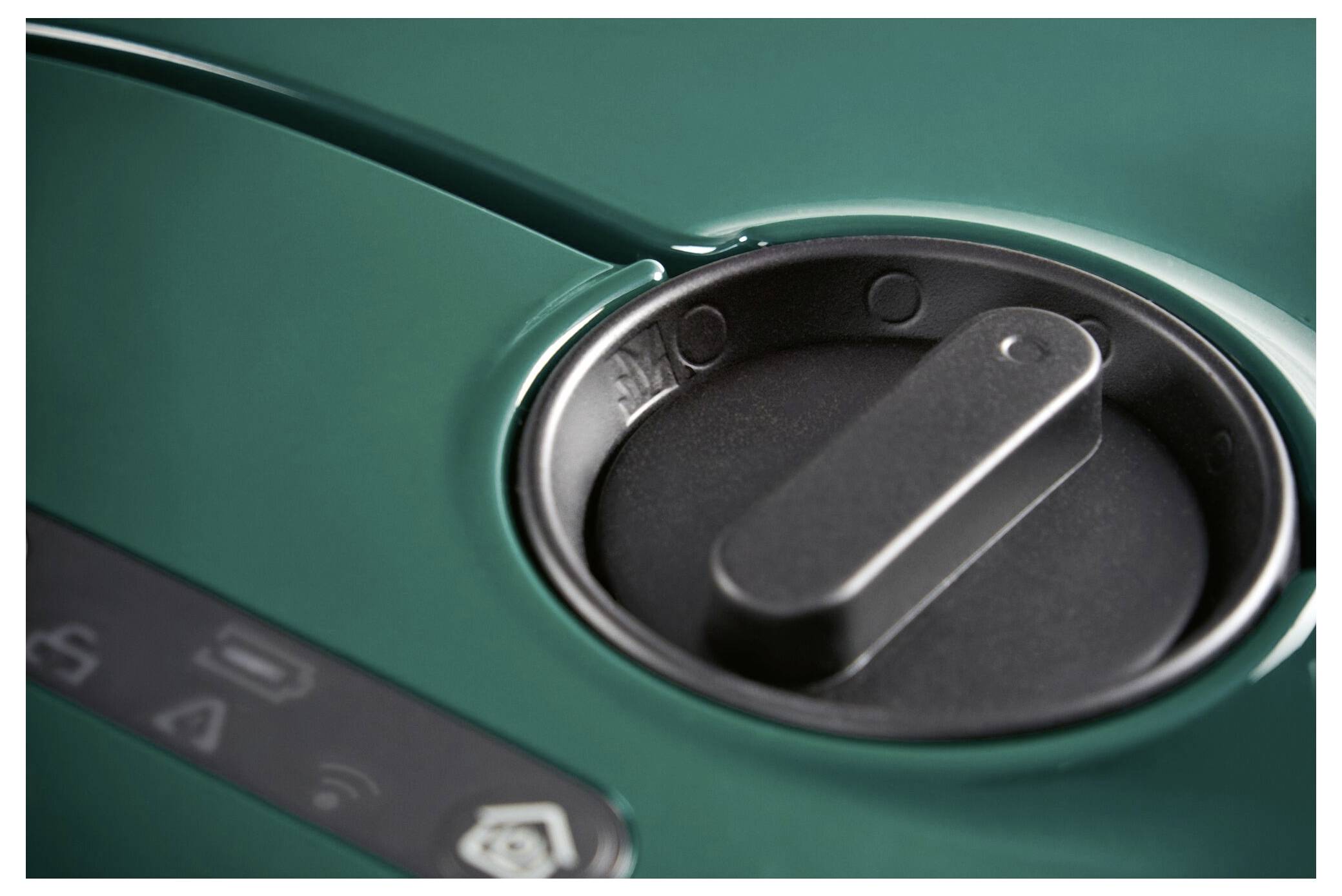 Green vehicle fuel cap in close-up, with partial symbols visible on the left, which may represent operating instructions.