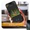 A hand is holding a smartphone displaying a photo of a deer in the woods. Text on the screen: 'Camera: Deer detected'.