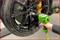 A person is tightening a wheel nut on a black car tyre with a green impact wrench.