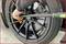 A person is tightening a wheel bolt with a torque wrench on a black car tyre.