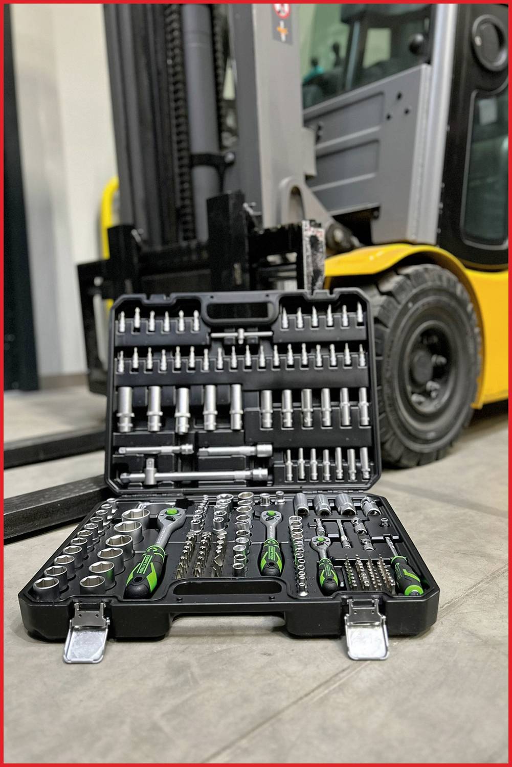 An open toolbox with various spanners and sockets is standing on the ground in front of a forklift truck.