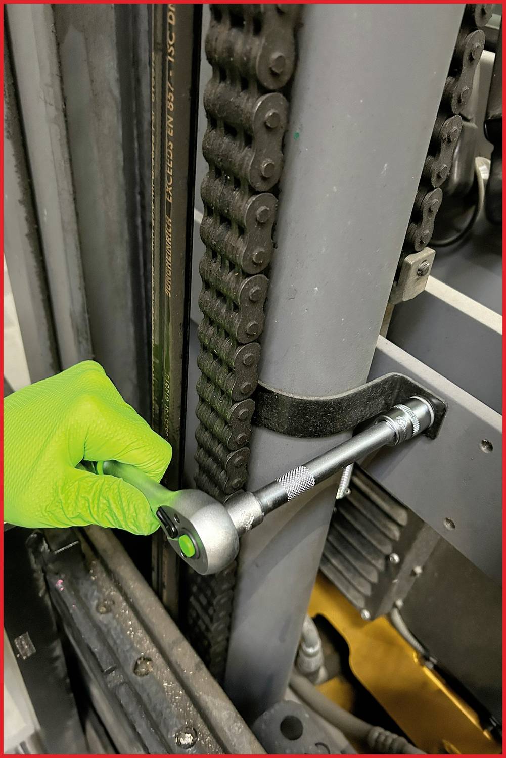 An open toolbox with spanners and socket wrenches is lying in front of a forklift in a workshop.
