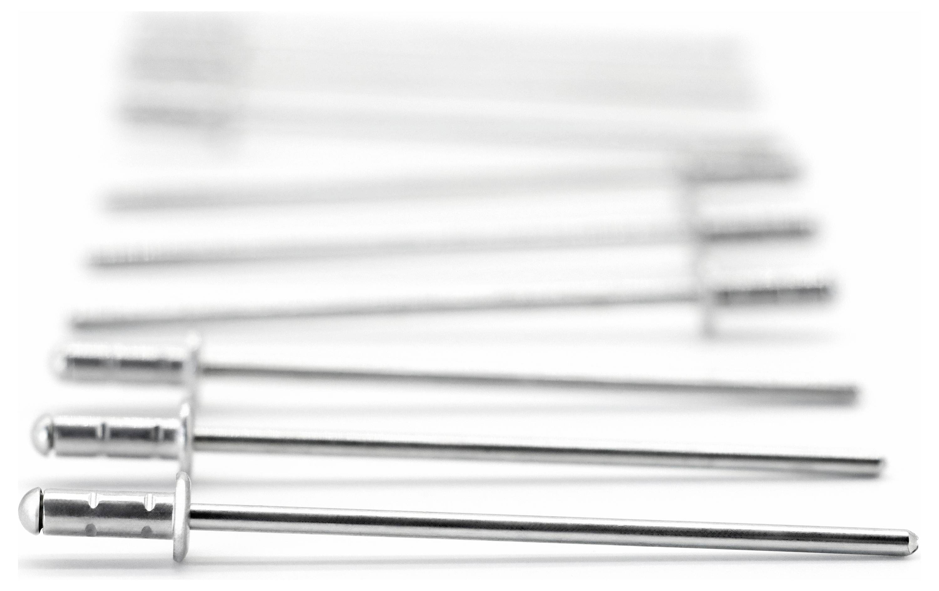 Several steel pins arranged in a line are in sharp focus in the foreground. In the background, the pins blur out of focus.