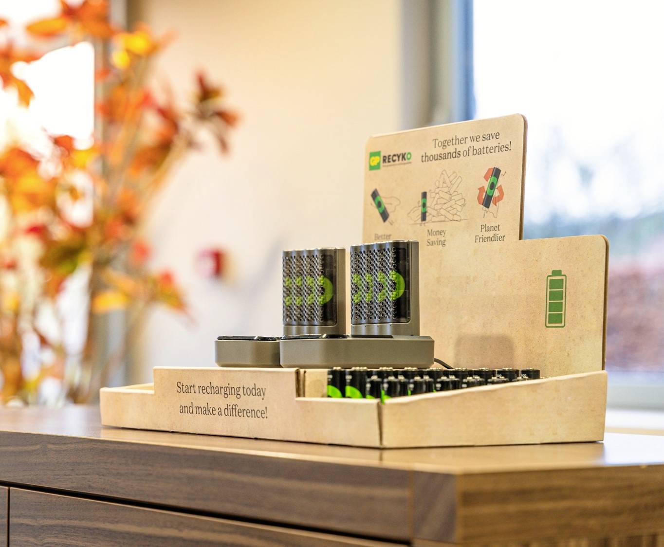 A charging station display with rechargeable batteries and signs highlighting the environmental benefits of recharging.